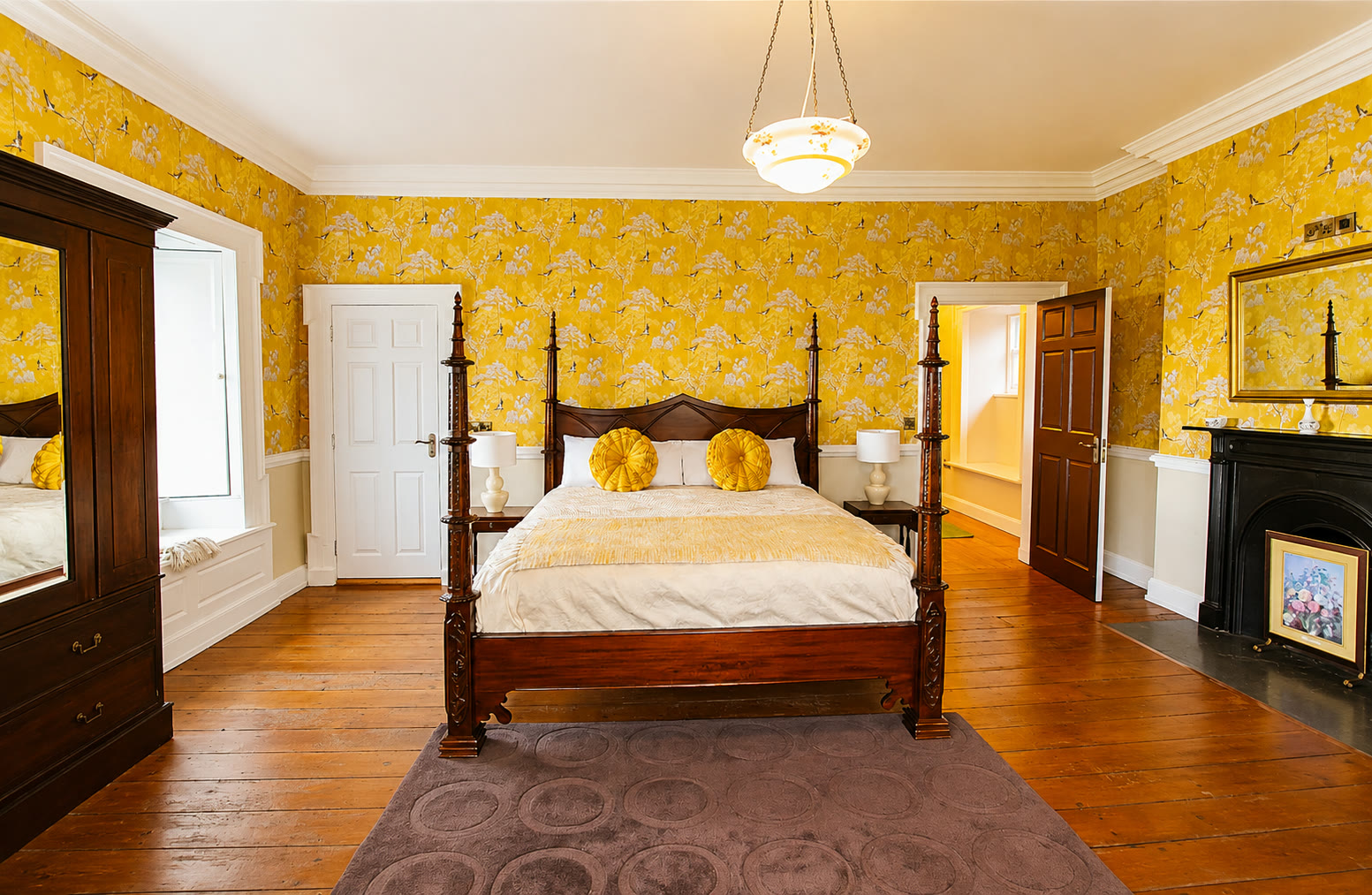 A guest bedroom with a four-poster bed and yellow chinoiserie wallpaper